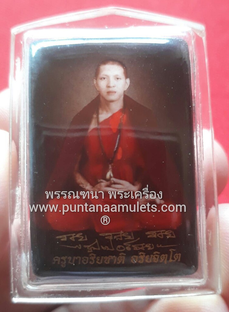 ล็อกเก็ตสี่เหลี่ยมรูปเหมือน(ฉากแดง) "ไตรมาส" ปี 52...ด้านหลัง...บรรจุ ผงพุทธคุณมหาเมตตา-มหาโภคทรัพย์ , ตะกรุดเงิน และเหรียญเม็ดแตง...ครูบาอริยชาติ อริยจิตโต วัดแสงแก้วโพธิญาณ จ.เชียงราย...